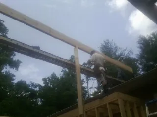 Carpenter setting a ridge beam over a new addition frame — Ice Dam Removal by Roofing Brothers in Benge