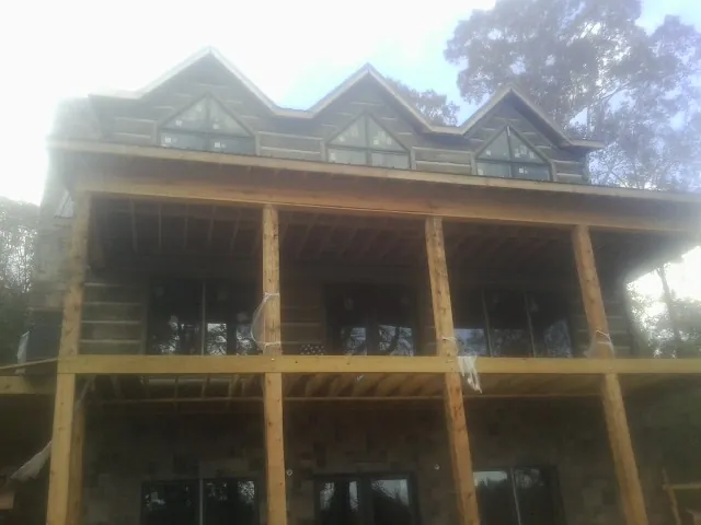 Dormers and porch framing on a large log home under construction — Roof Coating work by our crew in Benge
