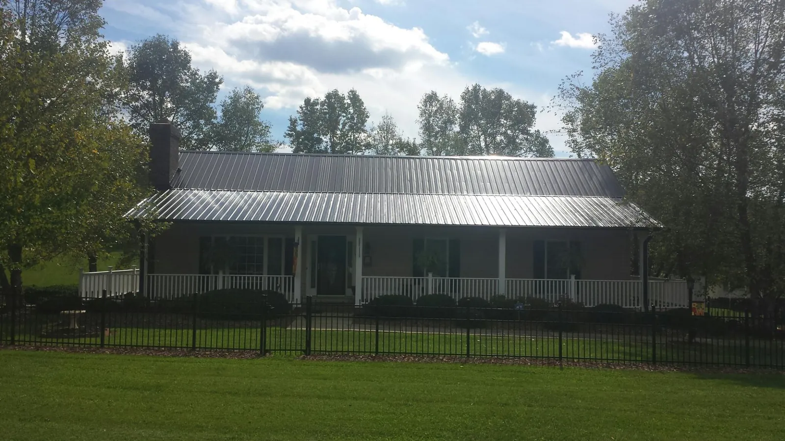 Gray metal roof on a brick ranch with a full width front porch — Gutter Guard Installation work by our crew in Benge